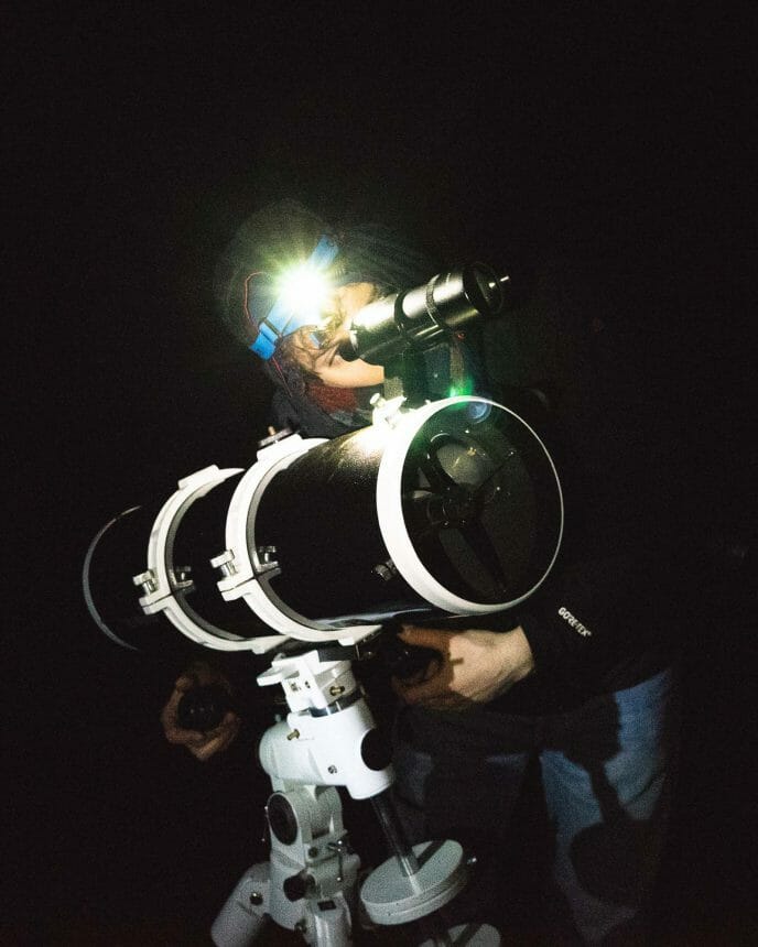 un homme manie un télescope de nuit