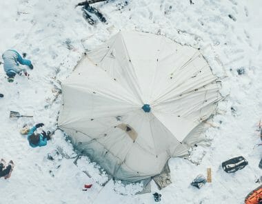 Des personnes montent un tipi dans la neige pour dormir en se protégeant du froid