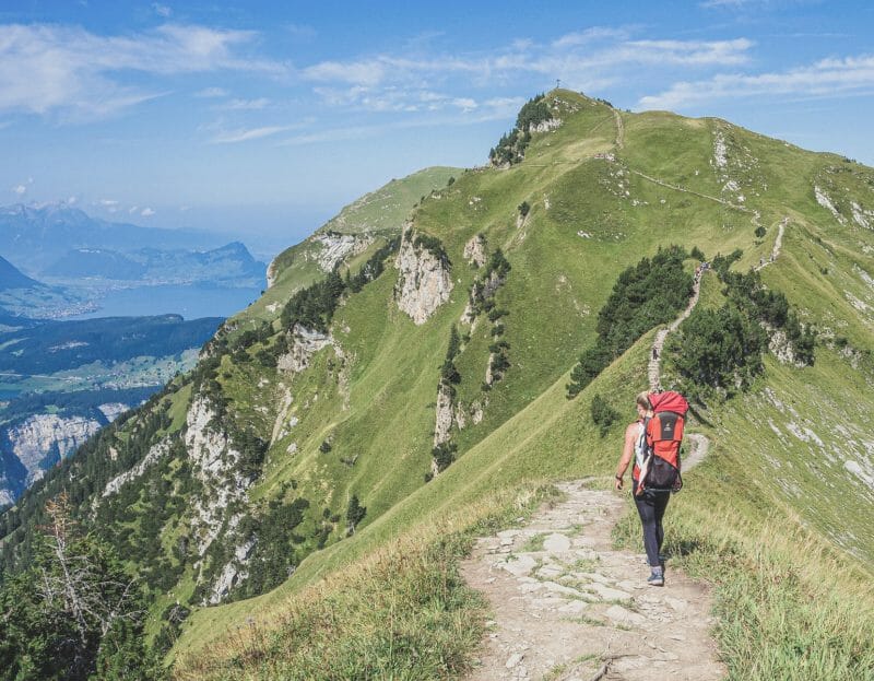 Une femme marche sur un sentier de grande randonnée en portant son bébé sur le dos