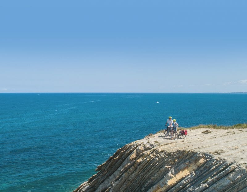 deux cyclistes sur une falaise regardent la mer