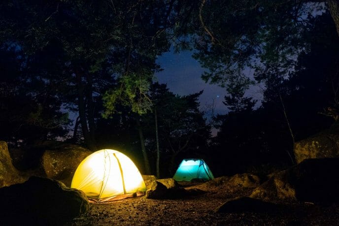 deux tentes illuminées en forêt la nuit