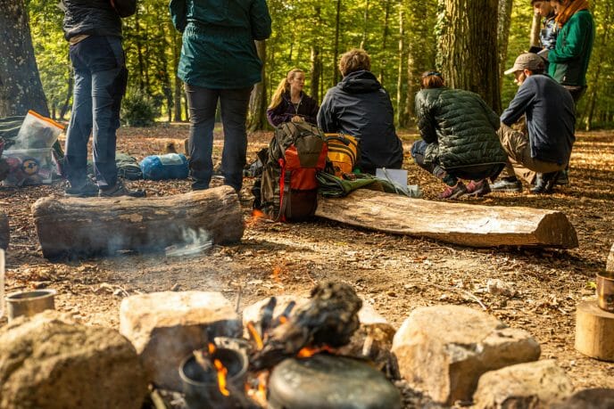 un groupe de randonneurs assis dans une forêt près d'un feu