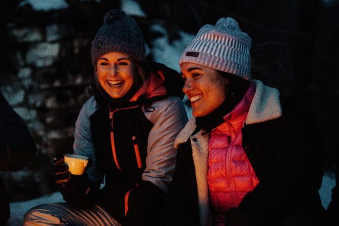 deux femmes de nuit autour d'un feu de camp dans une forêt enneigée
