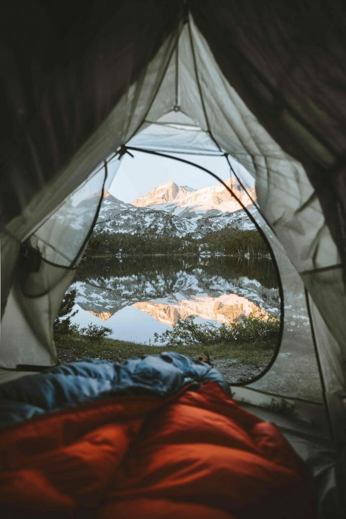 la vue sur un lac de montagne depuis l'intérieur d'une tente
