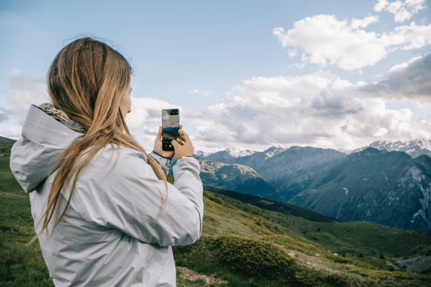 femme montagne qui prend une photo avec son téléphone devant paysage